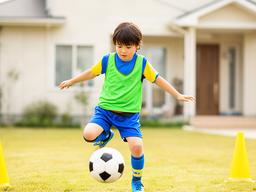 自宅前の安全なスペースでサッカーボールのリフティングを練習する子ども